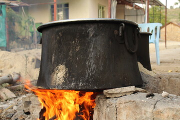An old black aluminum pot boiling on natural fireplace