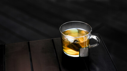 Hot Jasmine Green Tea with tea bag served in a cup isolated on dark background side view
