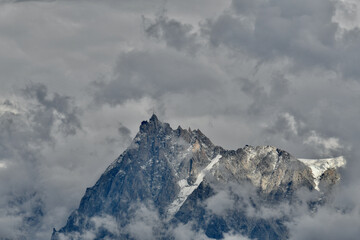 Fototapeta na wymiar The Aiguille du Midi in the middle of dramatic clouds. This is a 3,842-metre-tall (12,605 ft) mountain in the Mont Blanc massif within the French Alps. It is a popular tourist destination