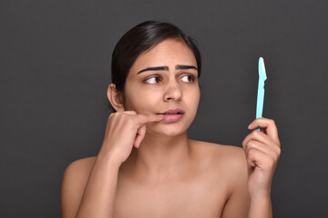 A young woman holding an eyebrow trimmer