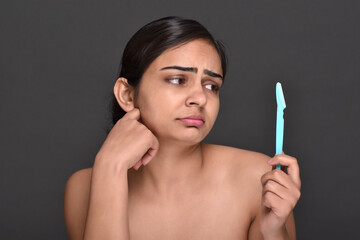 Obraz premium A young woman holding an eyebrow trimmer