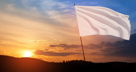 White flag waving in the wind on flagpole against the sunset sky with clouds. White flag is a symbol of surrender.