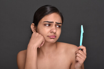 Obraz premium A young woman holding an eyebrow trimmer