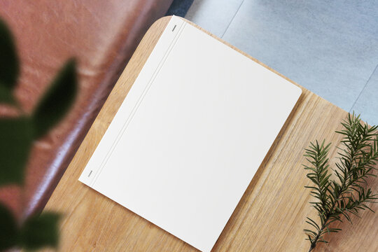 Clean minimal photo book 5x7 mockup on wooden table with conifer and leaves