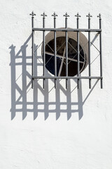 Round glass window surrounded by metal in house with white facade.
