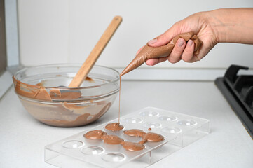 Filling a chocolate mold with a piping bag. Making chocolates concept
