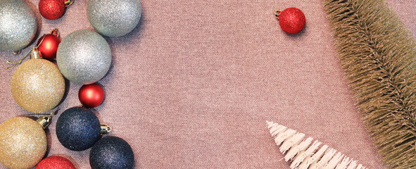 Christmas banner with Christmas balls and a small decorative golden and white Christmas tree. New Year's toys on the background of coarse fabric, burlap. Happy New Year. Christmas background