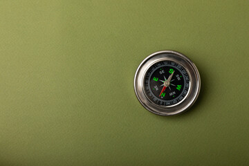 Classic round compass on green texture background. The concept of tourism with a compass. travel...