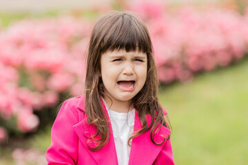 little girl in a bright pink suit is crying in the street