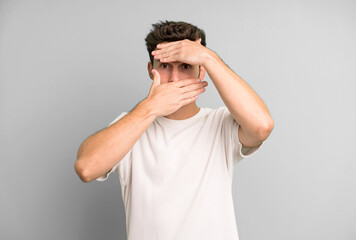 young handsome man covering face with both hands saying no to the camera! refusing pictures or...
