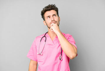 handsome teenager thinking, feeling doubtful and confused. nurse concept - obrazy, fototapety, plakaty
