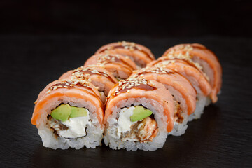 sushi roll with tuna, avocado and cream cheese on a black background.