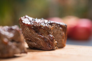 Closeup of grilled meat chunks served on wooden board
