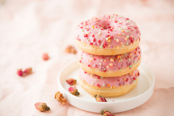 Three pink donuts with fudge are on a plate, selective focus