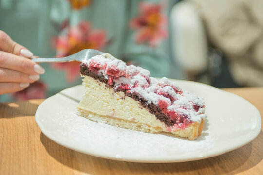 Closeup photo of woman eating piece of cake with raspberries