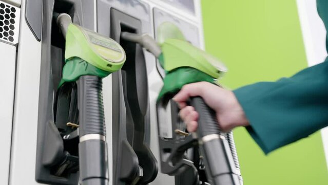 Woman at the fuel pump selects gasoline grade to fill the car with gasoline or diesel on a gas station. Hand with a gun close up