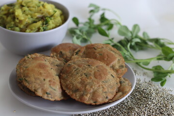 Bajra methi puri. Deep fried Indian flatbread made of pearl millet flour and fenugreek leaves. Served with spiced mashed potato gravy. Shot on white background.