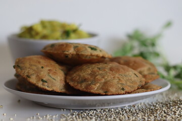 Bajra methi puri. Deep fried Indian flatbread made of pearl millet flour and fenugreek leaves. Served with spiced mashed potato gravy. Shot on white background.