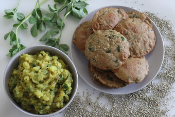 Bajra methi puri. Deep fried Indian flatbread made of pearl millet flour and fenugreek leaves. Served with spiced mashed potato gravy. Shot on white background.