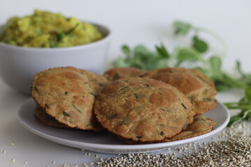 Bajra methi puri. Deep fried Indian flatbread made of pearl millet flour and fenugreek leaves. Served with spiced mashed potato gravy. Shot on white background.