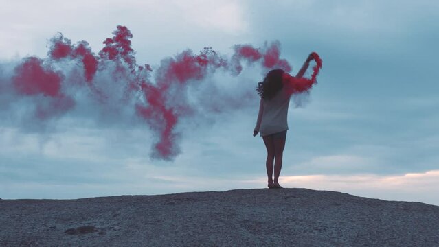 Red smoke bomb, beach and woman dancing for holiday celebration or vacation with energy, colorful pattern and blue sky. Art, energy and fireworks with young, adventure or gen z person jump and dance