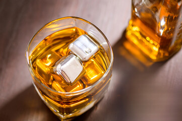 A glass of Whiskey with ice cube on wooden table