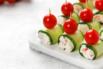 Appetizer Cucumber rolls stuffed with cream cheese, sweet pepper, tomatoes cherry over it, served...