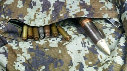 Soldier takes Bullets, shells, cartridges and projectiles on khaki camouflage backpack. Lend-Lease concept. Army concept. Sales of weapons and ammunition. Military industry, war, global arms trade.