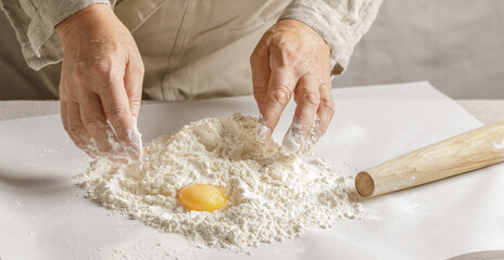 Women’s hands, flour and dough. A woman is preparing a dough for home baking. Concept of home...