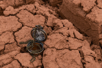Fototapeta na wymiar Antique pocket watch with a chain lies on cracked clay in the desert