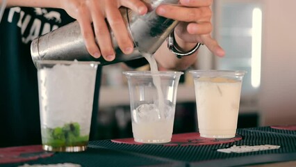 A bartender makes a cocktail with ice close-up in a disposable cup. A cocktail in a plastic container