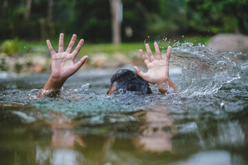A person drowns in the river reaching for help. Hand drowning children sticking out of the water.