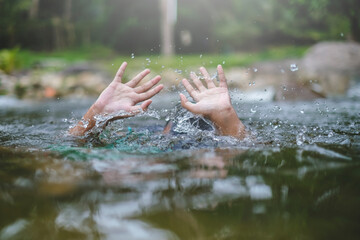 A person drowns in the river reaching for help. Hand drowning children sticking out of the water.