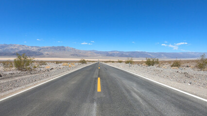 State Route 190 crossing Panamint Valley in Death Valley National Park, California, United States. Empty desert road in Death Valley with clear blue sky.