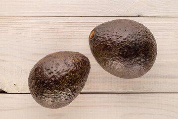 Two ripe avocados on wooden table, macro, top view.