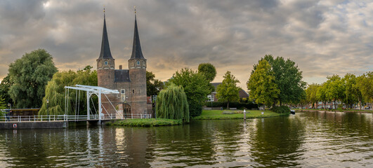 Panoramatic view of the medieval city gate Oostpoort along the canal by sunset in the city of Delft, The Netherlands