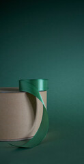 kraft paper cake box with green ribbon on dark green background