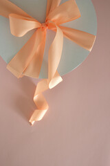 white paper cake box with peach ribbon on light pink background