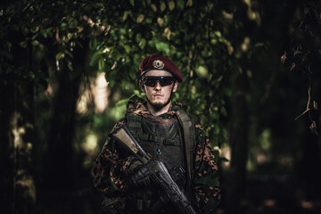 Fototapeta na wymiar Portrait of an eastern special forces soldier with rifle in woodland