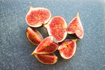 Close-up photo of a fig on a dark board. Ripe fruit whole and in pieces.