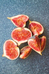 Close-up photo of a fig on a dark board. Ripe fruit whole and in pieces.