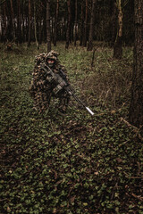 Eastern special forces soldier with rifle in woodland during autumn - 532517222
