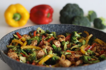 Stir fried vegetables with chicken in frying pan. Air fried chicken cubes tossed with sauteed bell...