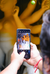 Boy taking photo of maa durga idaol from his phone.