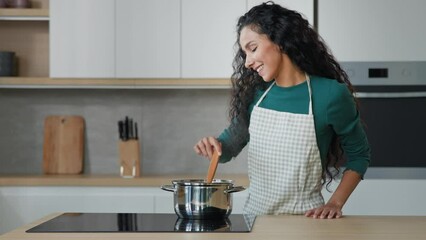 Beautiful female chef housewife cooking for family in kitchen healthy dieting food hot meal with aromatic smell. Arabian mother use culinary recipe of tasty soup home cookery with natural ingredients