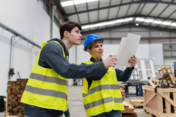 workers of a carpentry shop talking, mature female boss discusses showing plans, with young store...