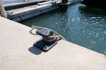Metal chain and rope wrapped around a Metal anchor point for boats, pier dock post.