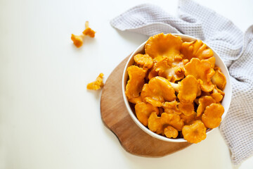 red chanterelle mushrooms in a white plate on a light gray table