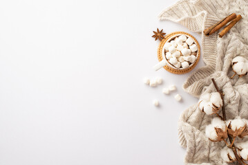 Winter mood concept. Top view photo of mug of hot drinking with marshmallow on rattan serving mat knitted scarf cotton branch anise and cinnamon sticks on isolated white background with empty space