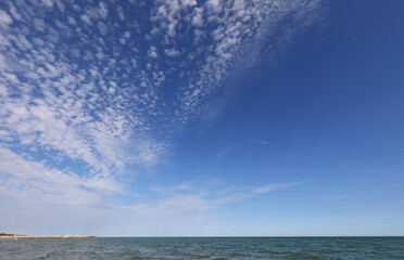 wide panorama with deep blue sky and white clouds and the sea calm
